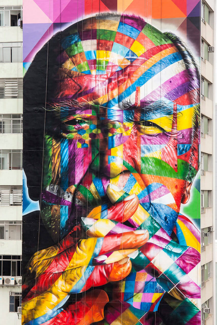 Fig. 2 – Mural de Eduardo Kobra na Avenida Paulista, de 2013, retrato do arquiteto Oscar Niemeyer. No trabalho pode–se ver referências a várias obras de Niemeyer, como o Palácio do Planalto, a Pampulha e o Museu Oscar Niemeyer. Foto de Alan Teixeira. Arte urbana.