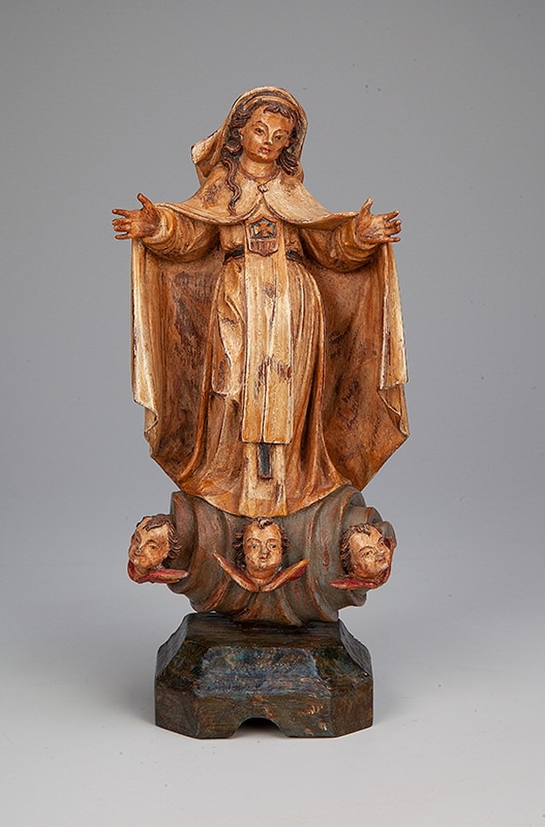ANTONIO FRANCISCO LISBOA, The Aleijadinho. Our Lady of Mercy. Polychrome wood image, characteristic of an early stage, with simpler drapery without many creative break-ins. The face is typical, the folds of the panejanento, the configuration of the clouds with three little angels attest to the authorship of Aleijadinho. 27 cm high. Brasil, 21st century. XVIII.