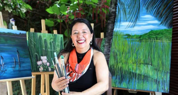 Elza Suzuki with canvas from the Cantos exhibition & Charms - Piratininga Lagoon. Photo: Disclosure / Macarena Lobos.